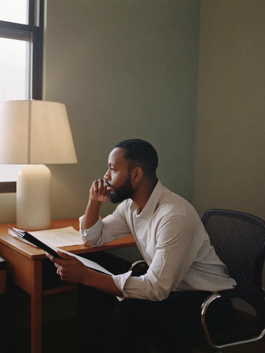 A psychologist in a private consulting room mid-session, attentive, notepad in hand